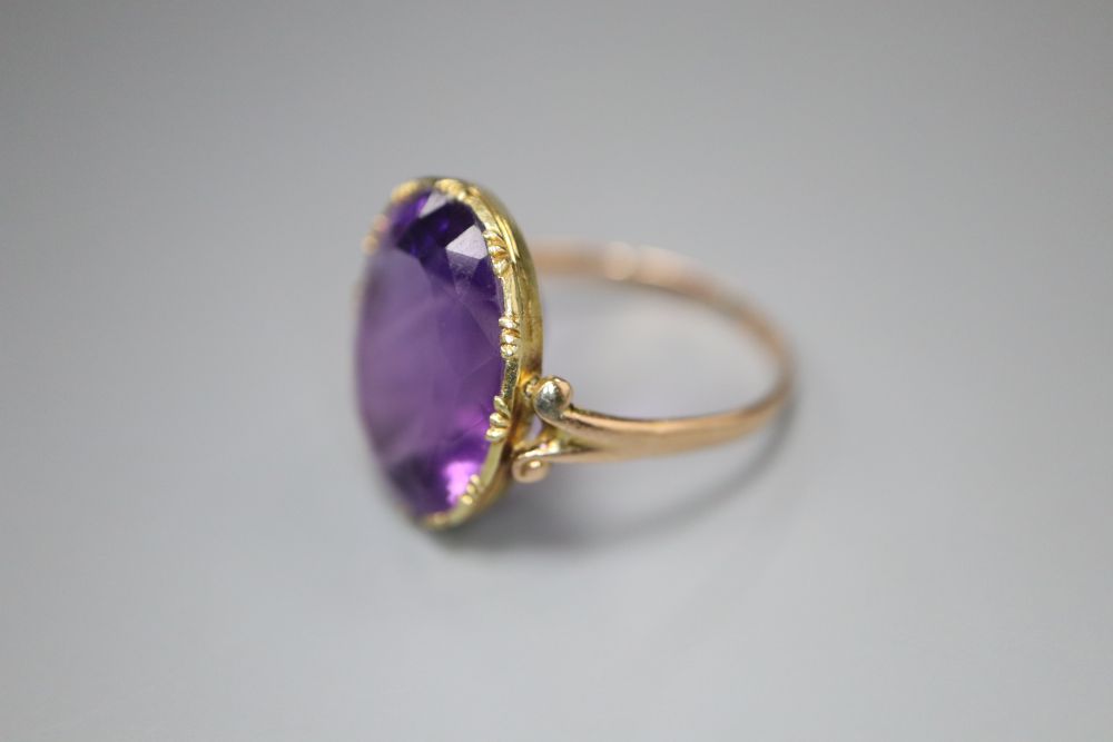 A 19th century gold and amethyst dress ring (tests as 9ct), with collet setting and carved scrolled shoulders